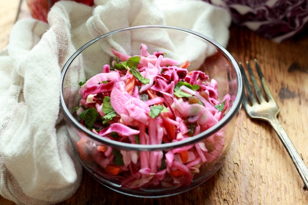 pickled vegetables in a glass bowl with a napkin and fork on the side