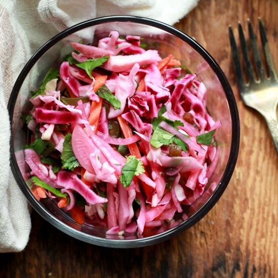 pickled vegetables in a glass bowl with a napkin and fork on the side