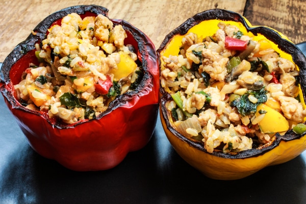 stuffed yellow bell peppers with turkey and rice on a wooden board