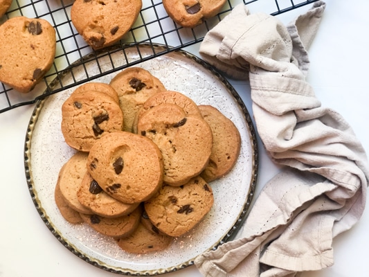 miso chocolate chip cookies on a white plate with cookies on a cooling rack behinds