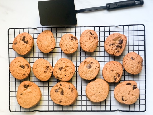 miso chocolate chip cookies on a cooling rack with a black spatula on the side