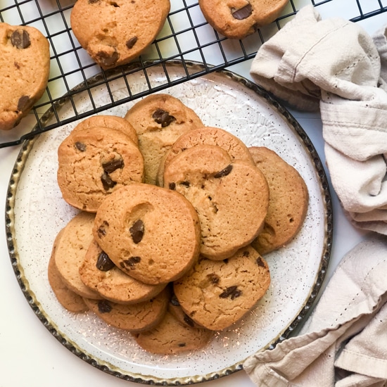 miso chocolate chip cookies on a white plate with cookies on a cooling rack behinds