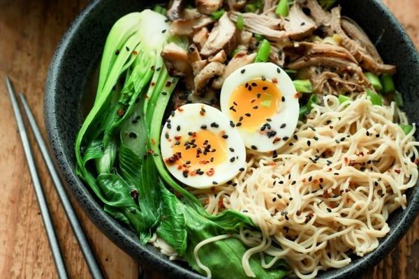 a bowl of pulled pork ramen with two runny eggs on top