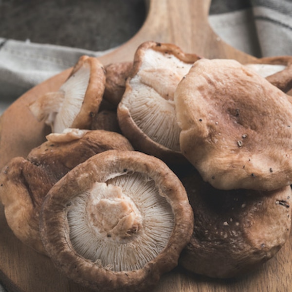 Sliced shiitake mushroom on wooden cutting board.