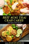 Mini crab cakes stacked on a wooden board with a side of aioli dipping sauce and fresh limes