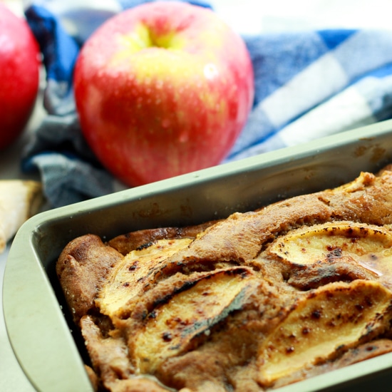 apple ginger bread in a loaf pan with red apples in the background