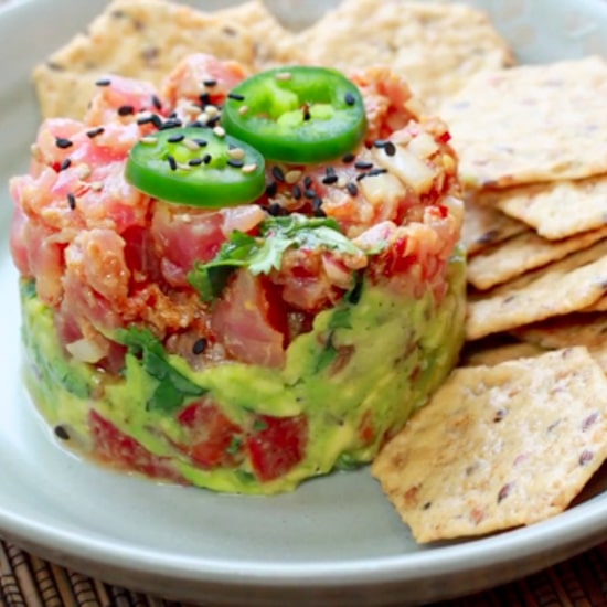 Vibrant Ahi tuna napoleon topped with jalapeño slices on a plate with sesame chips on the side.