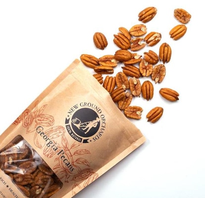 a bag of Georgia pecans on top of a white surface with loose pecans coming from the bag