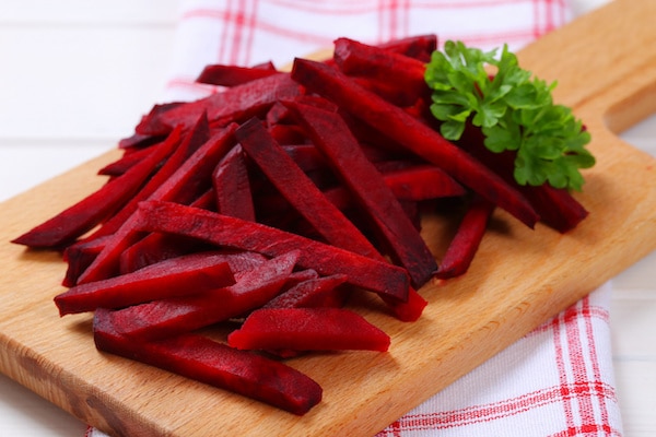 Raw red beets cut into strips on a wooden cutting board