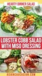 A platter of vibrant lobster cobb salad on top of romaine greens and a clear jar of miso dressing on the side.