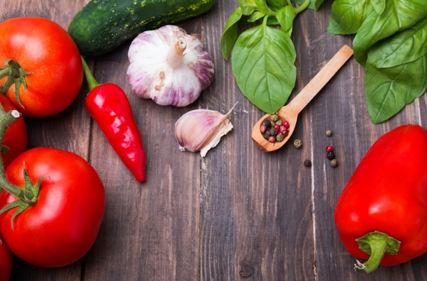 Tomatoes, pepper, basil, cucumber, and garlic on wooden table, ingredients for gazpacho