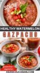 Three white bowls filled with spicy watermelon gazpacho on a white wooden board, with ingredients on the side: a tomato, basil, and basil.