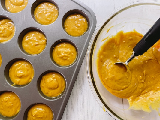 Pumpkin muffin batter in a glass bowl and in batter filled in a muffin tin.
