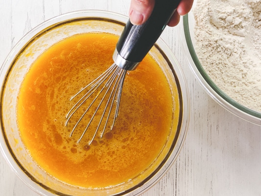 A woman whisking wet ingredients for making homemade pumpkin muffins.