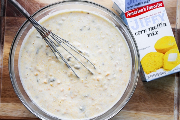 Batter for making skillet jalapeño corn bread in a large glass mixing bowl with a package of Jiffy corn muffin mix on the side.