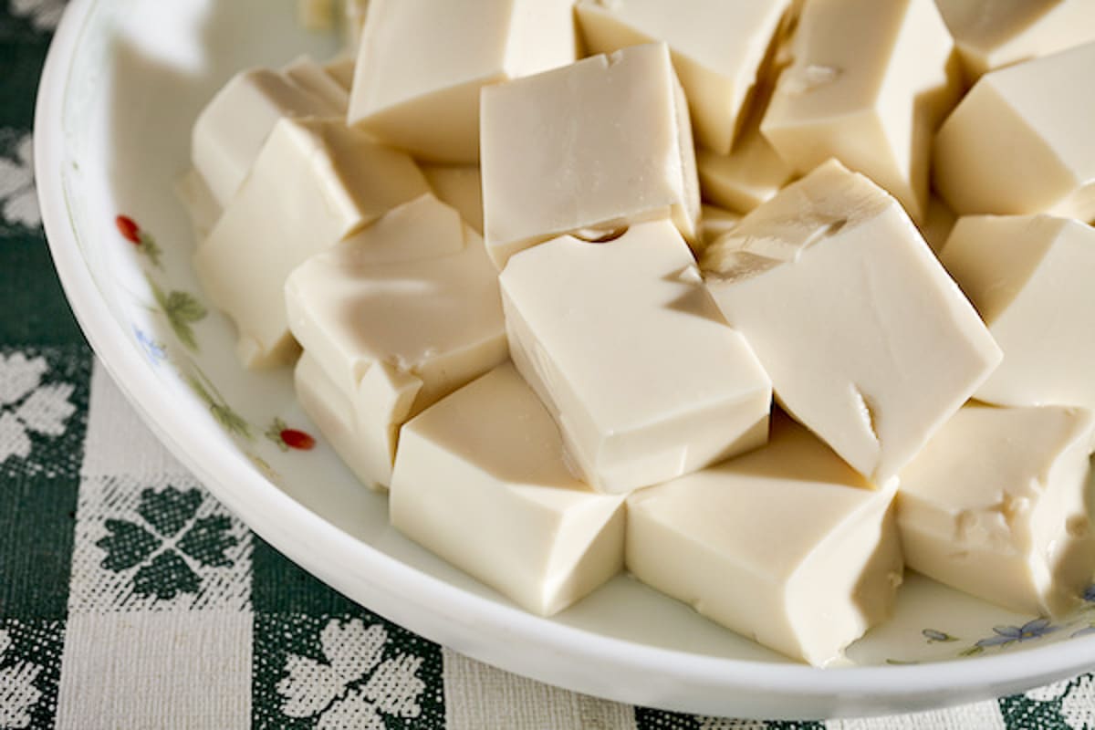 Cubes of silken tofu in a white bowl on top of a green and white napkin.