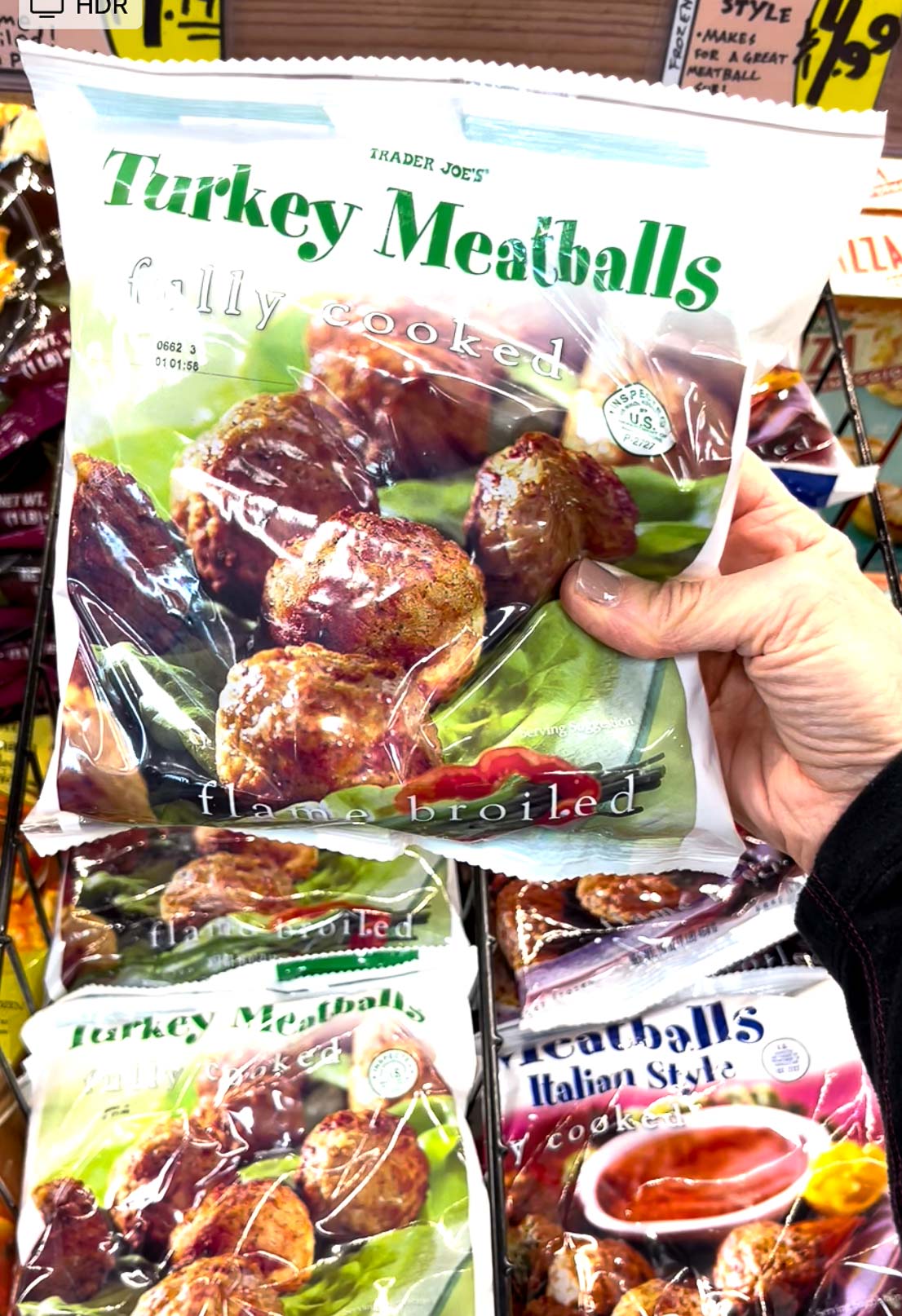 A hand holding up a package of Trader Joe's turkey meatballs.