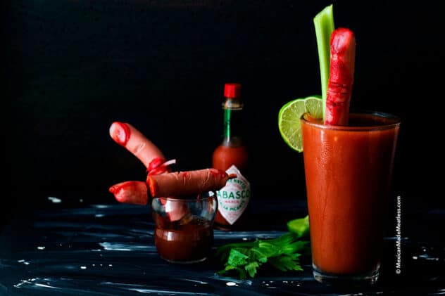 creepy, bloody Halloween severed fingers made out of hot dogs sitting on top of bloody mary cocktails