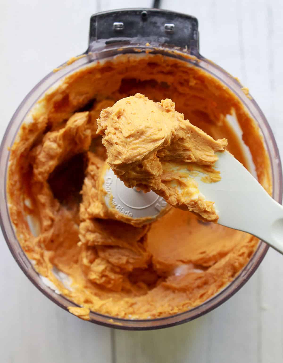 Miso butter in a food processor with a white knife holding up some of the butter
