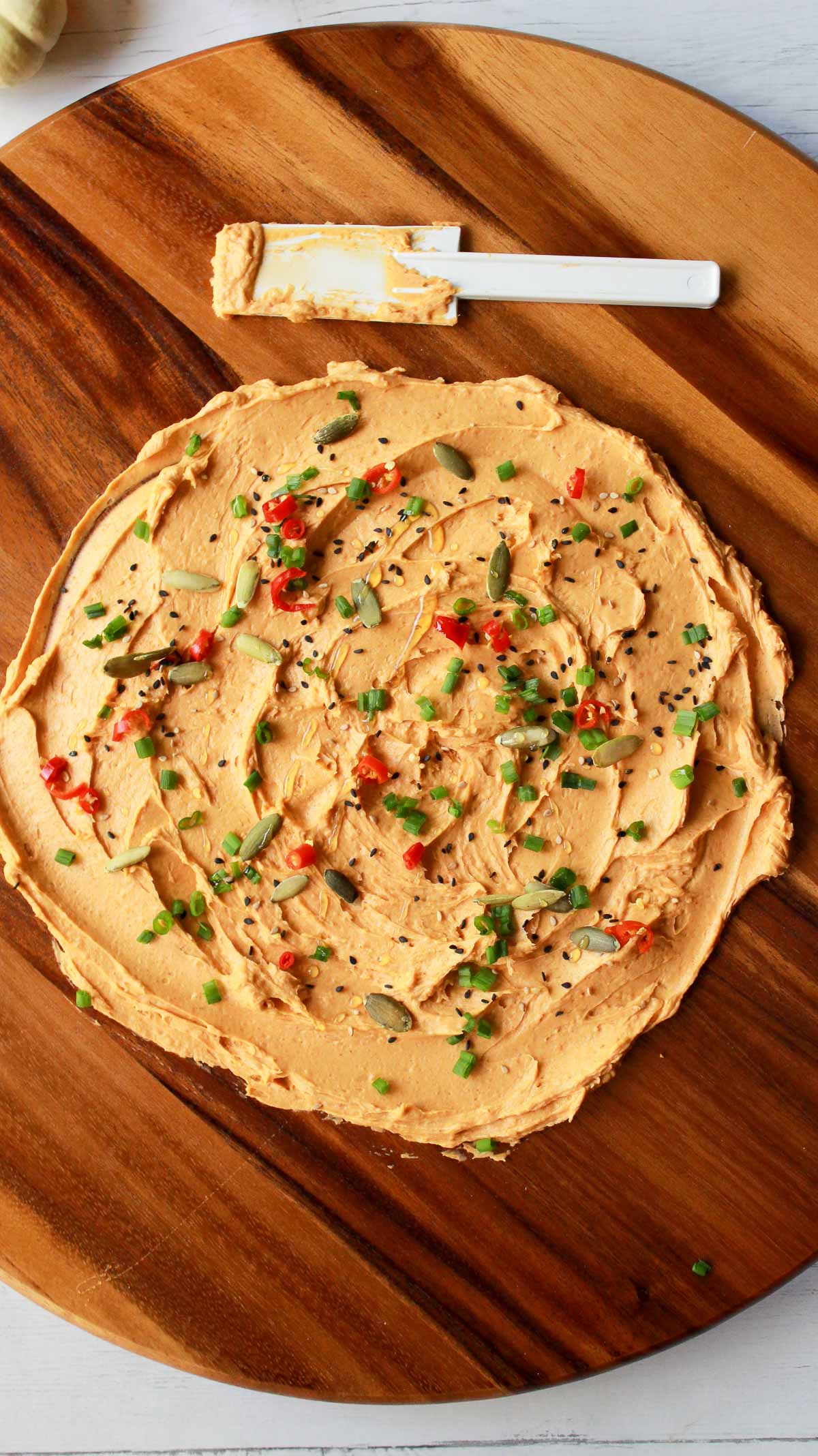miso butter with toppings spread onto a round wooden board with a white spreader on the side