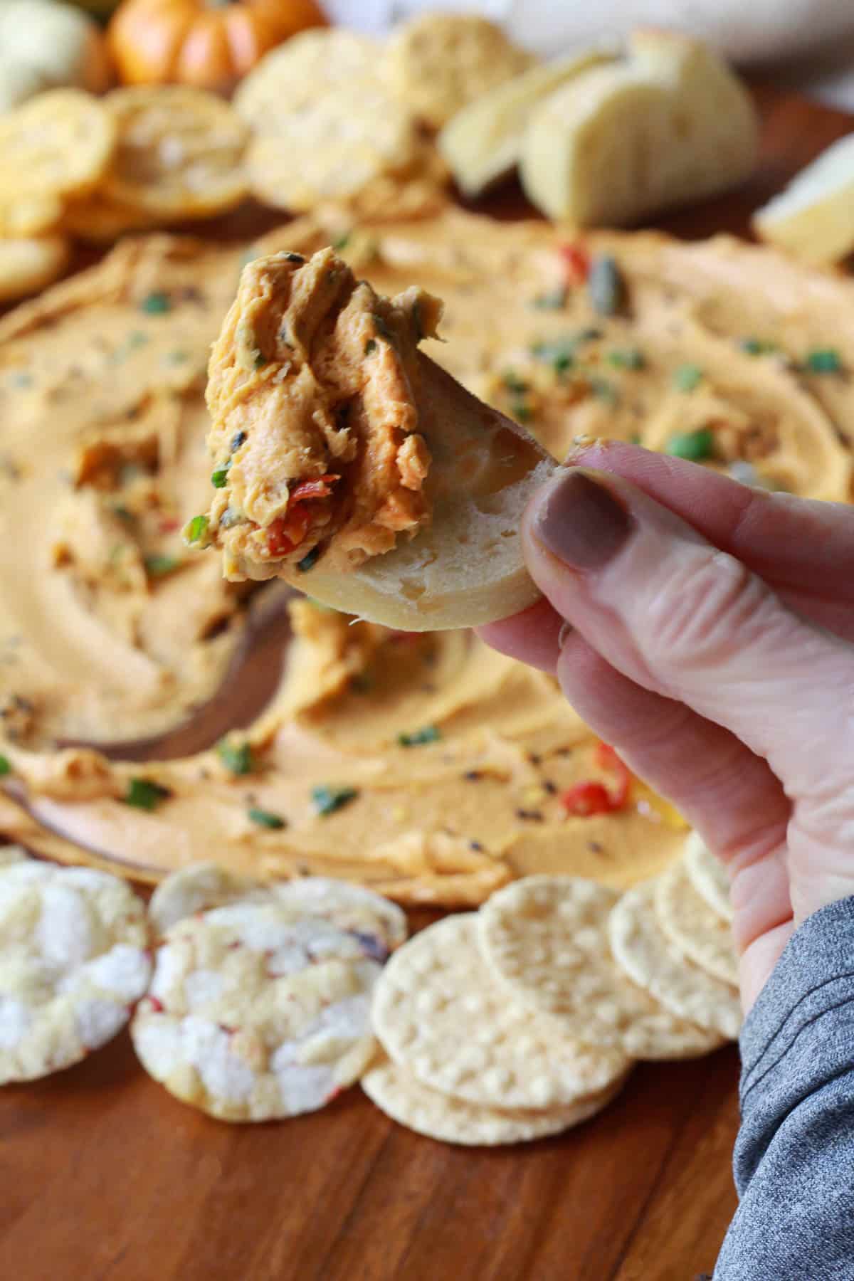 a hand holding up a slice of bread spread with miso butter over a miso butter board surrounded by crackers and bread