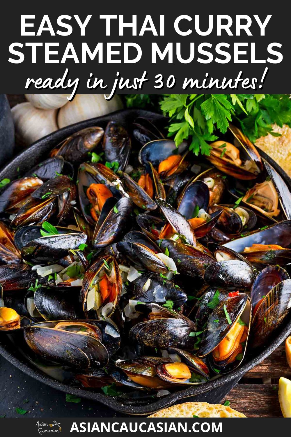A large pot filled with steamed mussels garnished with red chili peppers and cilantro and garlic and herbs on the side on top of a wooden board.