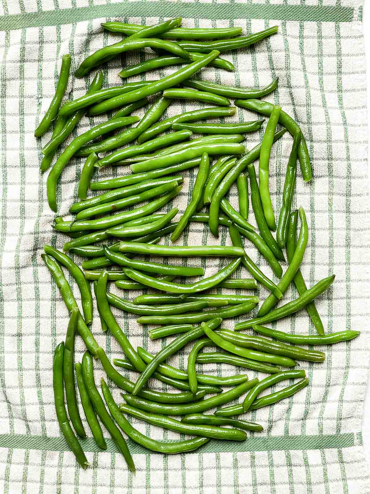 Green beans drying on a checkered kitchen towel.