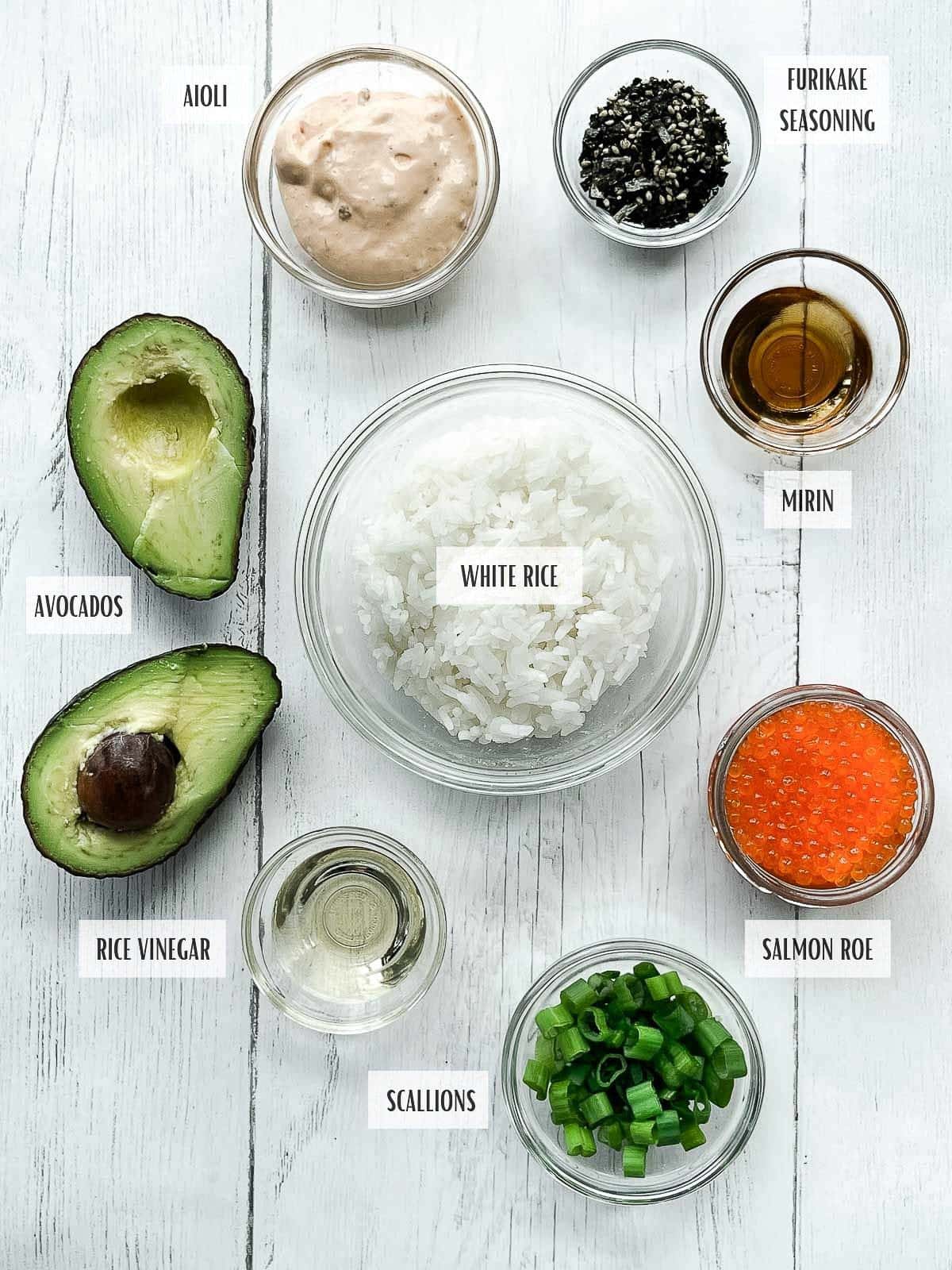 Labeled ingredients in glass bowls for making Sushi Waffles with Salmon and Tuna on top of a white surface.