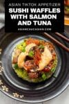 Sushi waffles with salmon and tuna on two round plates with a side of chopsticks on top of a white surface with a napkin on the side.