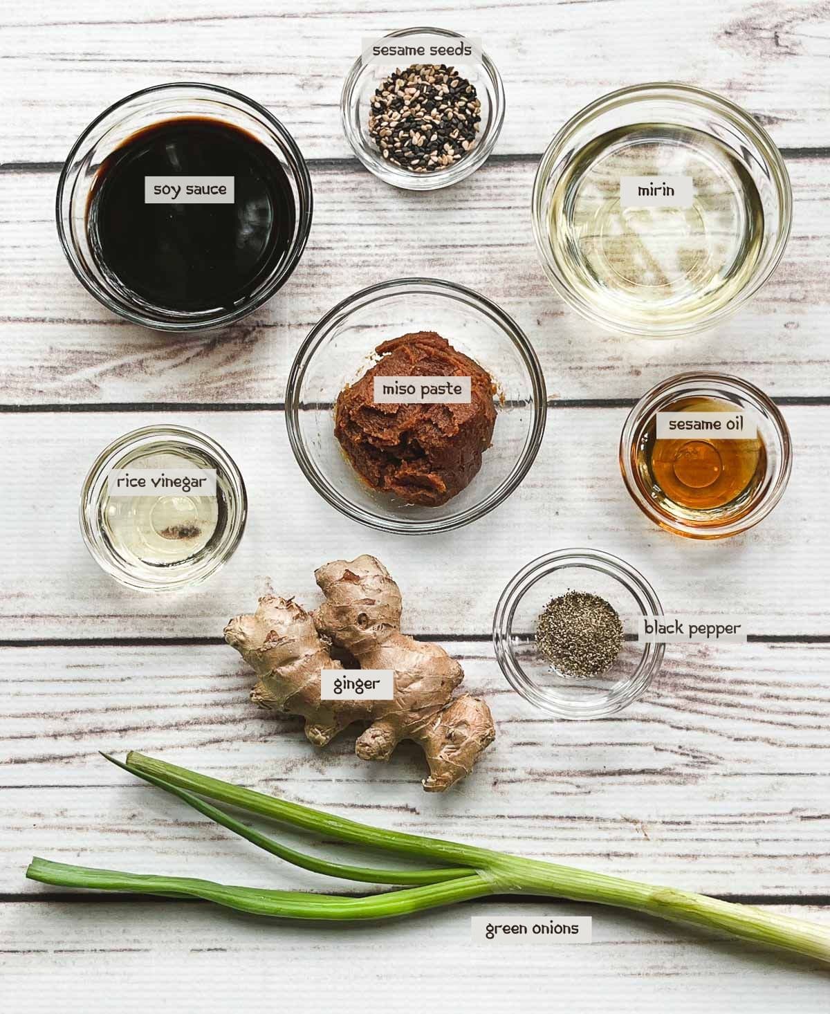 Labeled ingredients in small glass bowls for making a miso marinade, on top of a white board.