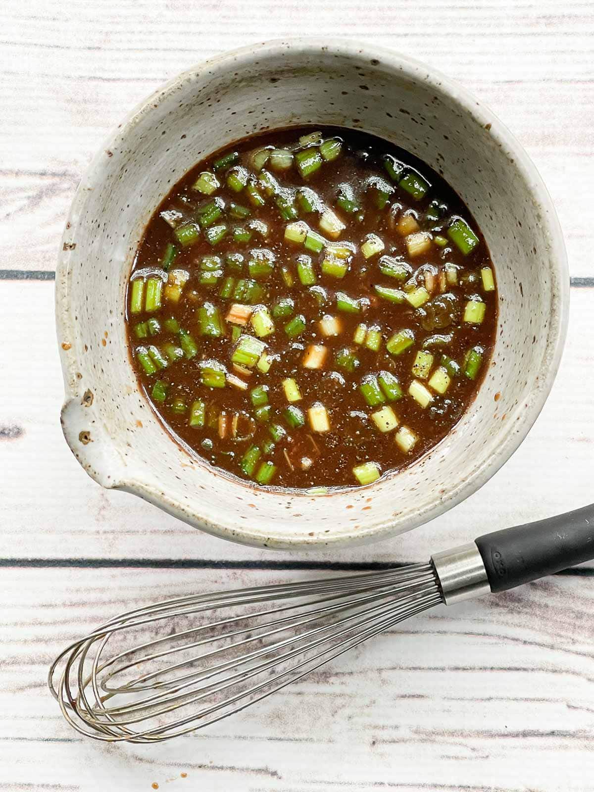 A miso marinade in a gray bowl with a whisk on the side on top of a white board.