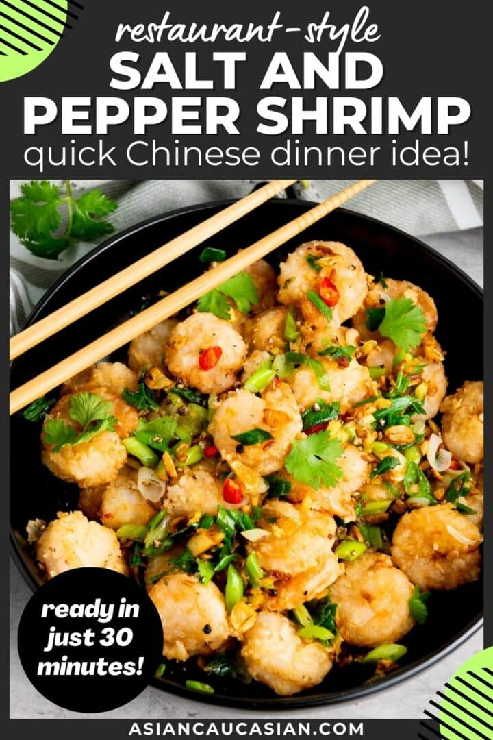 Chinese salt and pepper shrimp in a black bowl with sautéed vegetables and herbs, and a pair of chopsticks on top on a gray surface with a gray linen on the side.
